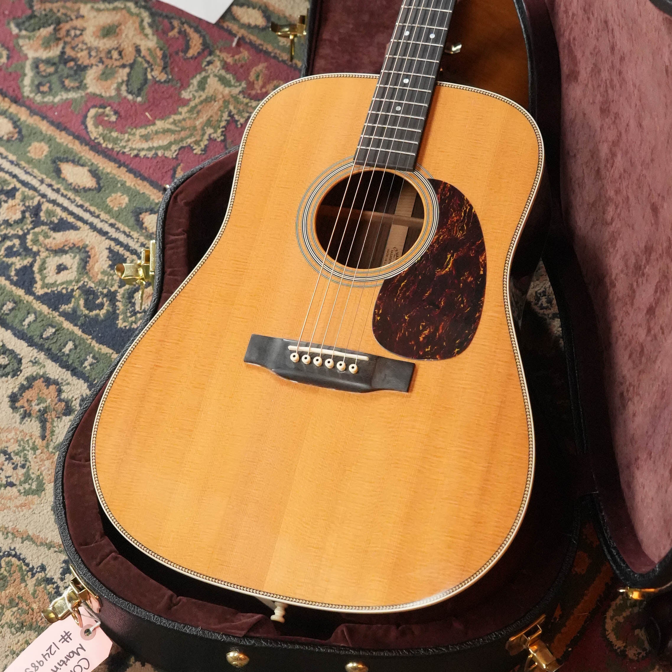 A (Used) 2007 Martin & Co. HD-28 Solid Sitka Spruce/East Indian Rosewood dreadnought acoustic guitar (#9851) with a natural finish rests in an open, velvet-lined hard case on a patterned rug, featuring six strings and a tortoiseshell pickguard.