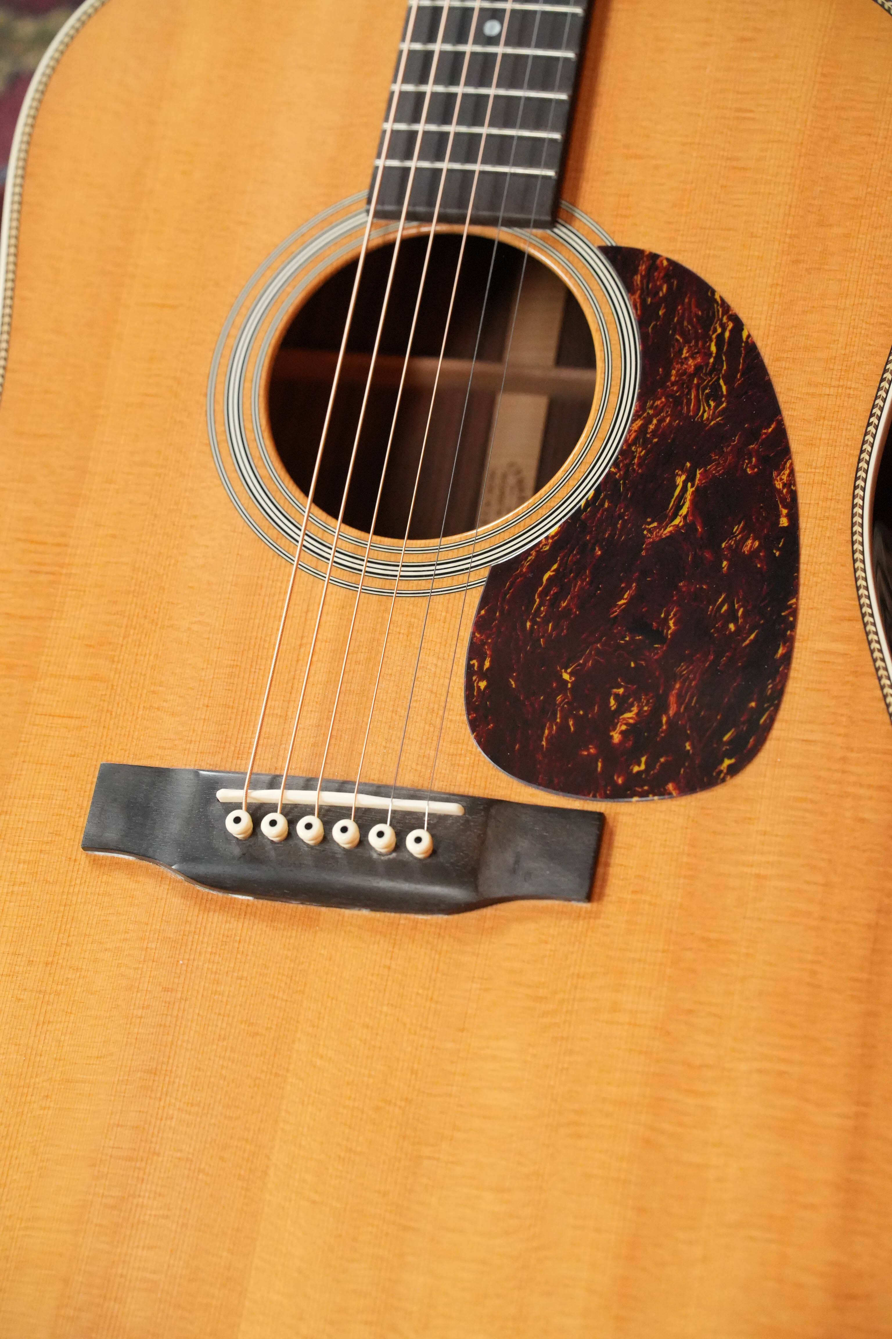Close-up of a 2007 Martin & Co. HD-28 Dreadnought Acoustic Guitar (#9851), showing its solid Sitka spruce top, East Indian rosewood body, strings, sound hole, and a dark marbled pickguard on the right.