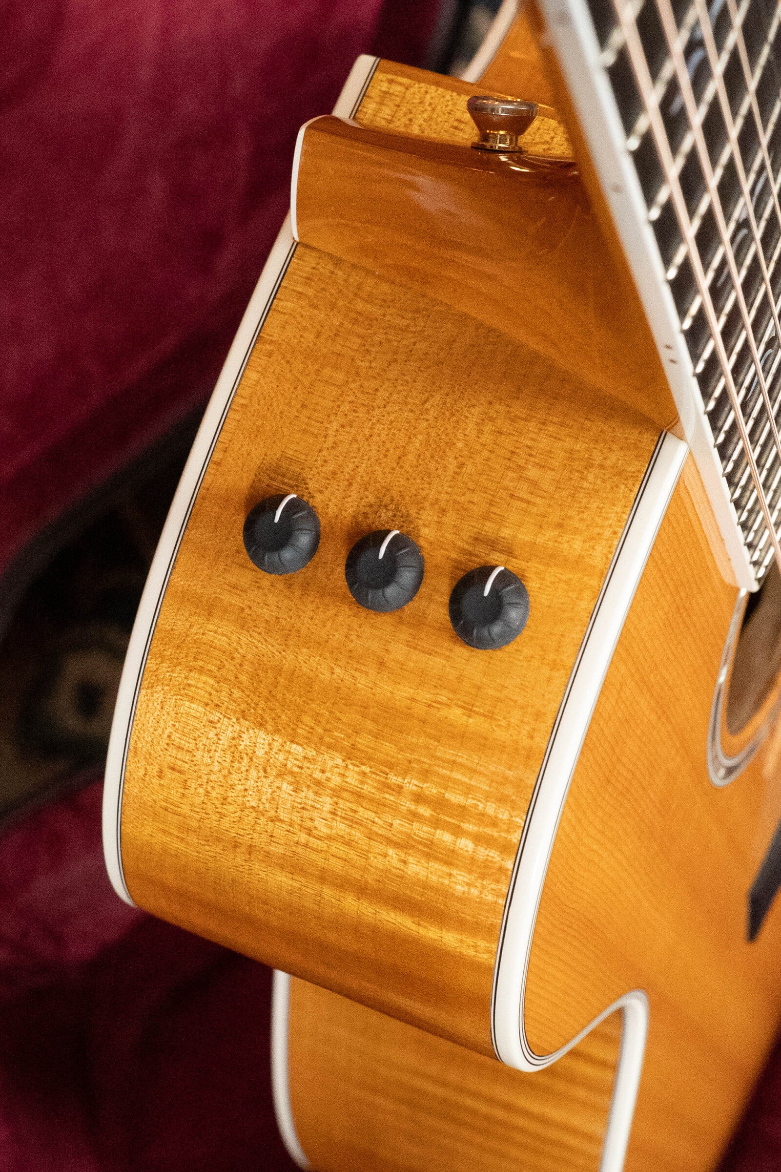 Close-up of a (Used) 2009 Taylor 614CE Torrefied Sitka/Maple Grand Auditorium guitar by Taylor Guitars, showing three black side control knobs near the neck, with glossy light wood finish and white binding.