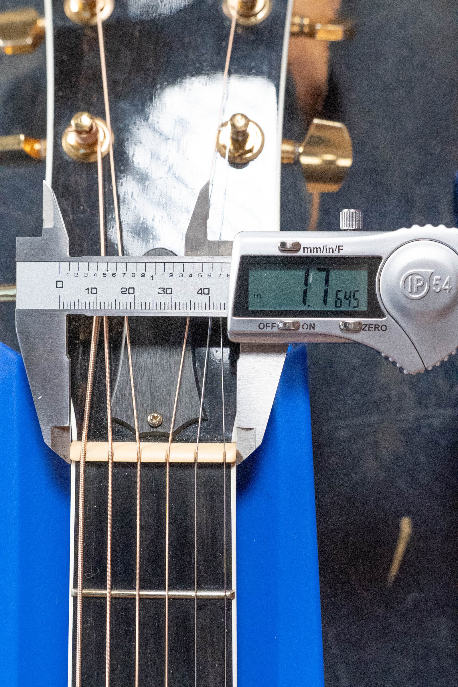 A digital caliper measures the nut width of a (Used) 2009 Taylor Guitars 614CE Torrefied Sitka/Maple Grand Auditorium Cutaway (#5110) at 1.7645 inches; it features gold tuning pegs and six strings.