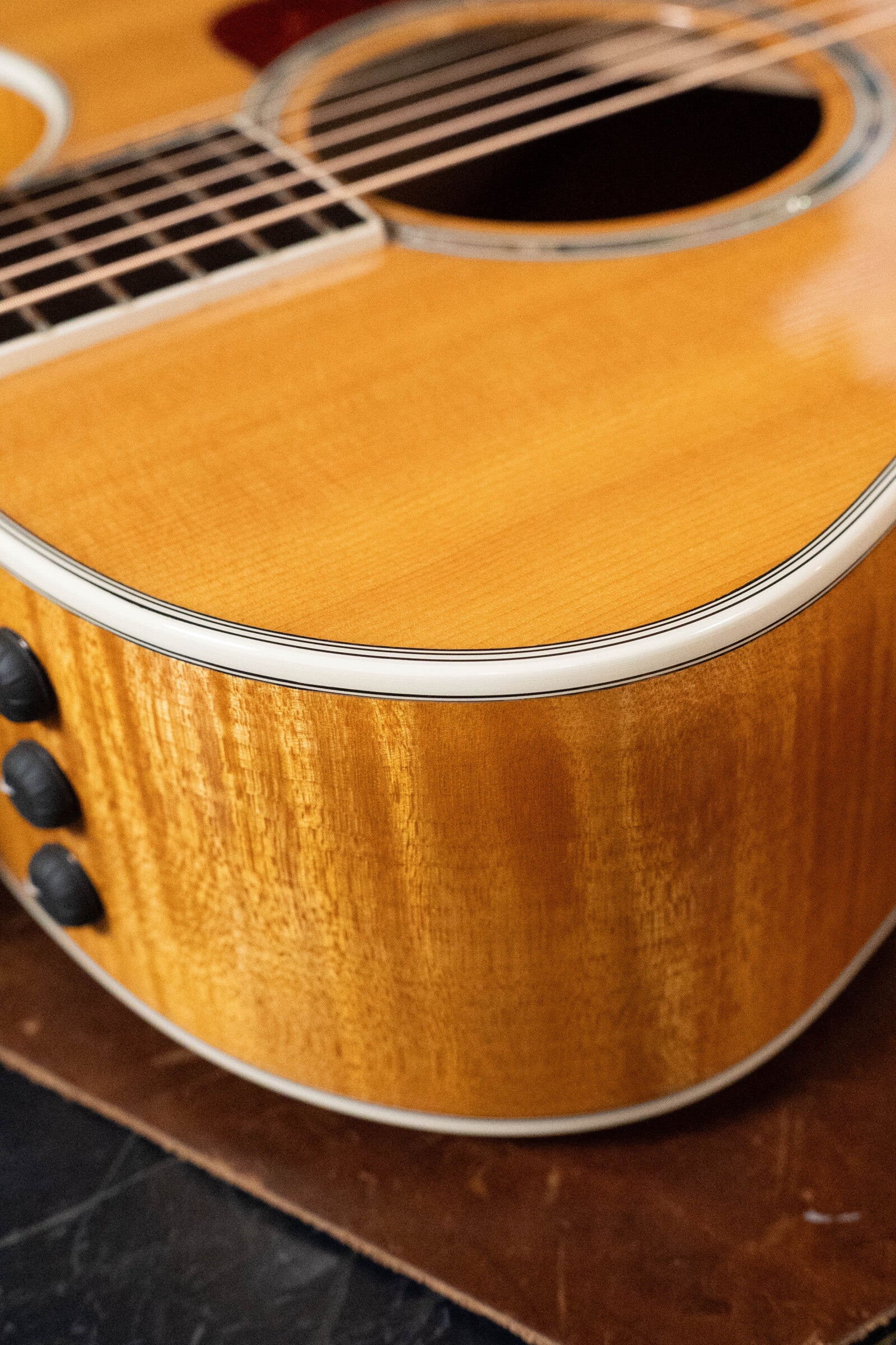 Close-up of a (Used) 2009 Taylor Guitars 614CE Grand Auditorium, showing its torrefied Sitka spruce top, maple body, white binding, side controls, and the neck and strings at the top.