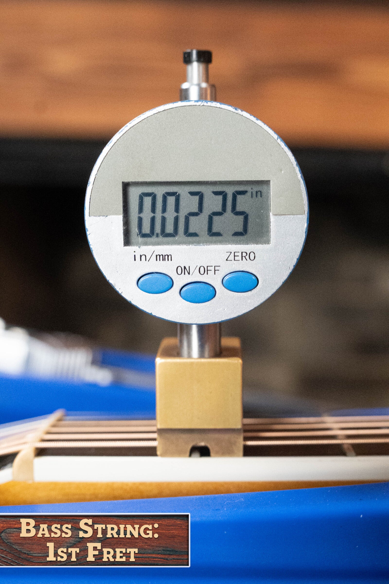 A digital gauge shows 0.0225 inches measuring bass string height at the 1st fret on a (Used) 2009 Taylor 614CE Torrefied Sitka/Maple Cutaway Grand Auditorium Guitar w/Pickup #5110 by Taylor Guitars. Wooden label: BASS STRING: 1ST FRET.