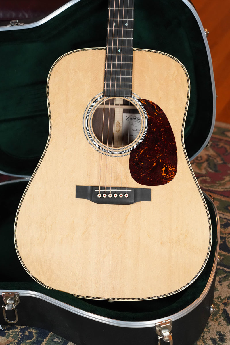 A Martin & Co. *Dread-Not Certified Used* 2021 Custom Shop HD-28 Bearclaw Sitka/East Indian Rosewood Dreadnought Acoustic Guitar #5218 rests in an open, black hard-shell case with green lining on a patterned rug.
