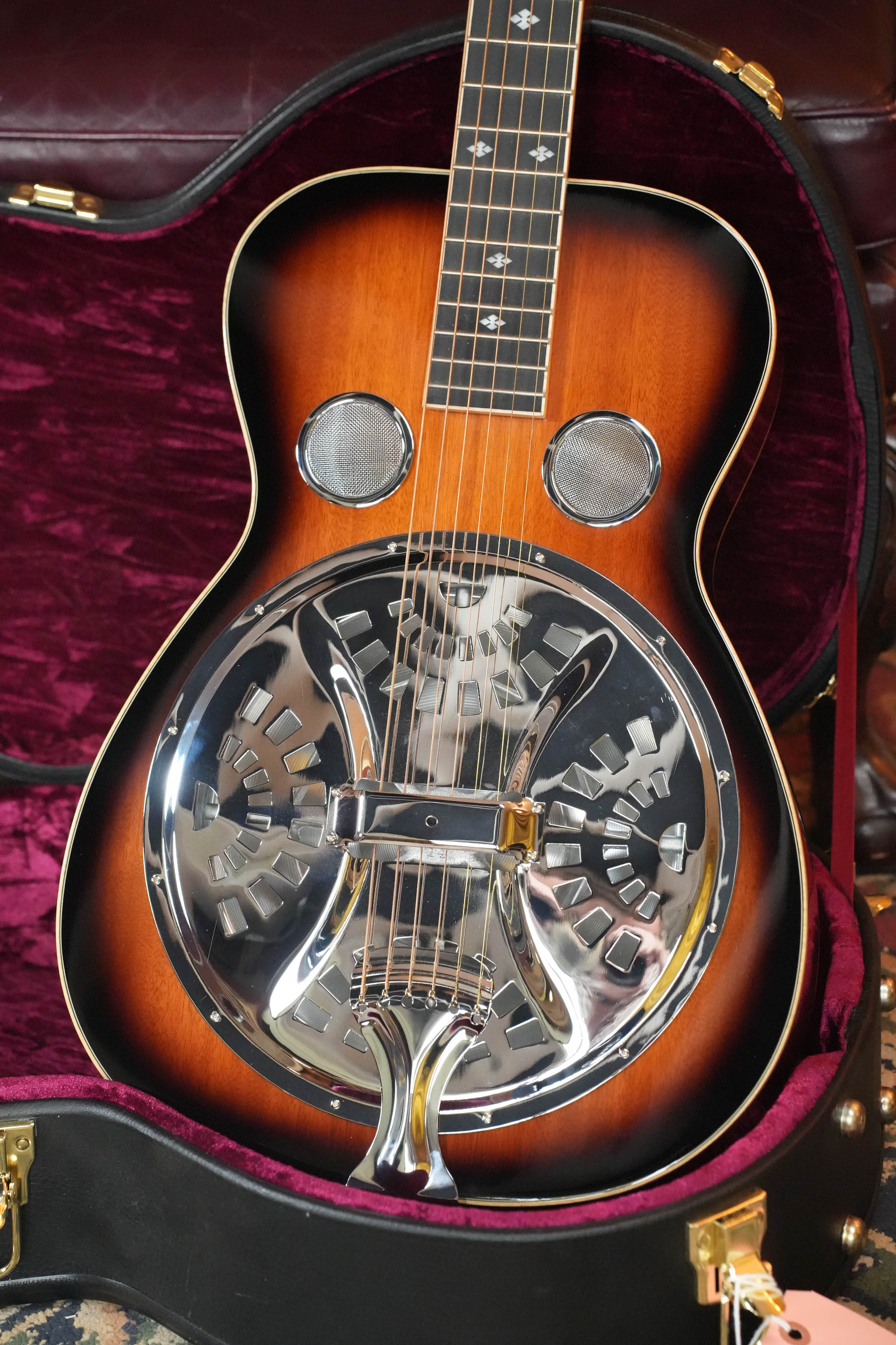 A used 2022 Gold Tone PBS-D Paul Beard Deluxe solid mahogany square-neck resonator guitar (#8165) with a sunburst finish rests in a plush purple-lined hardshell case, featuring metal cones and decorative fingerboard inlays.