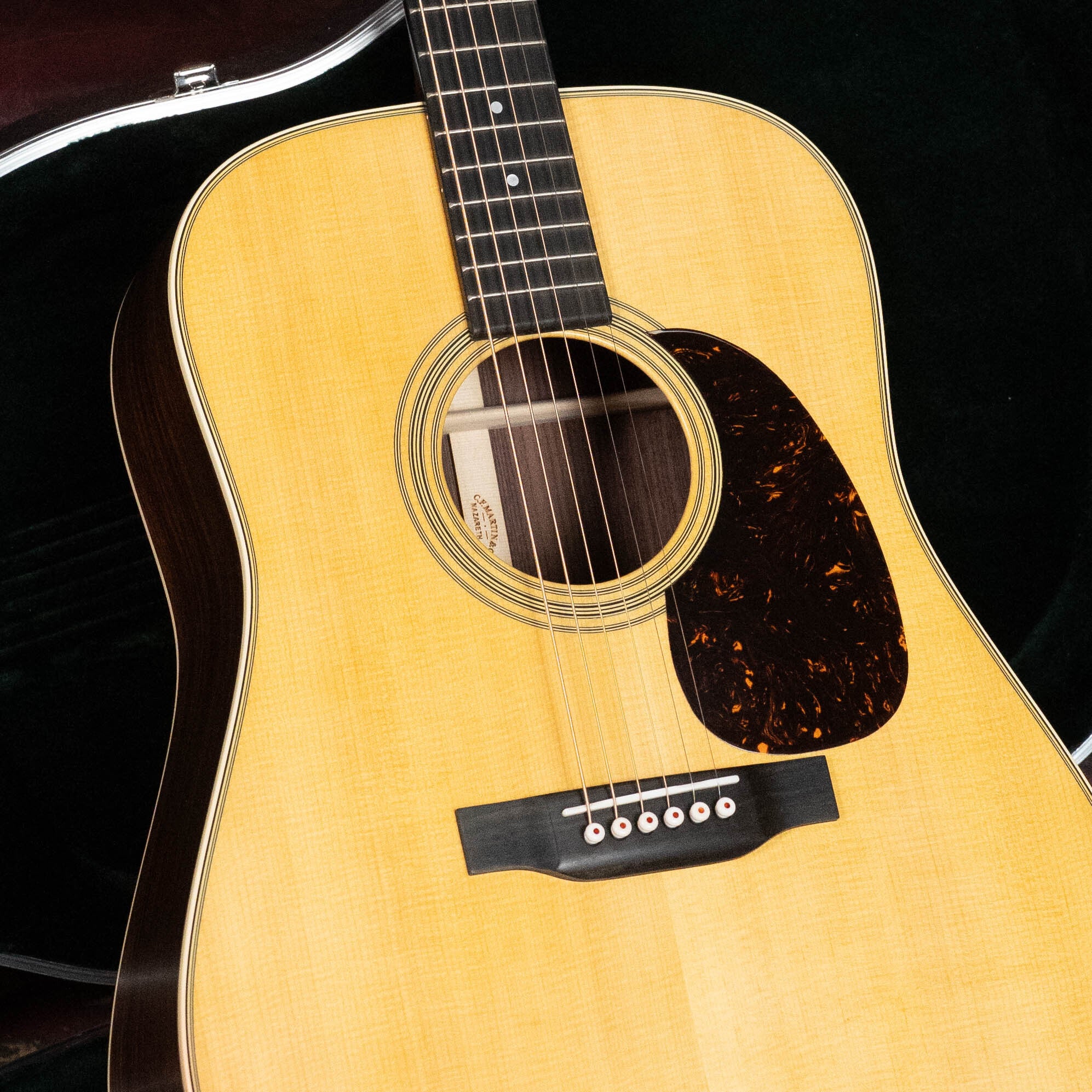 A close-up of a (Used) 2023 Martin & Co. D-28 Sitka/Rosewood Satin Dreadnought Acoustic Guitar (#2573), featuring six strings, solid Sitka spruce top, dark pickguard, and satin finish, resting in an open black case.