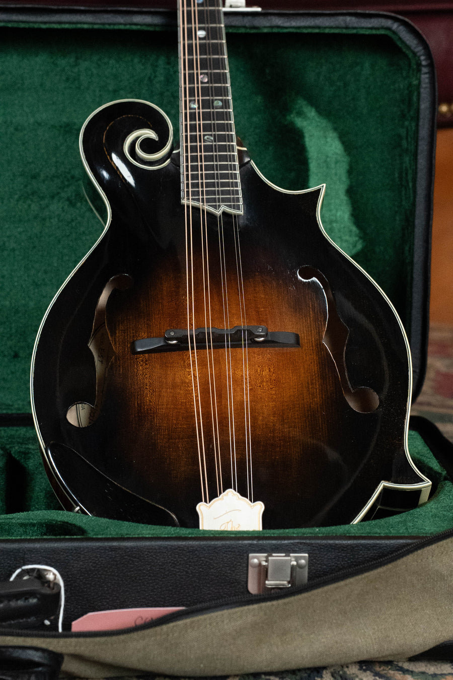 The Buford F-5T Torrefied Adirondack/Maple F-Style Mandolin (#011, 2025) features a dark sunburst finish, ornate scrollwork, and hand-carved details. Its torrefied Adirondack spruce top delivers exceptional tone and resonance. Comes in a green velvet-lined case.