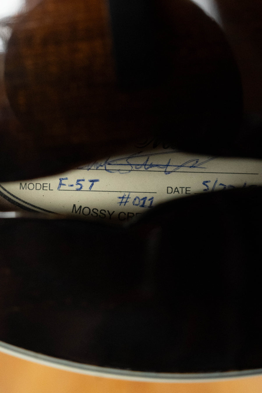 Close-up of a Buford sound hole label with handwritten details: (New - Player Wear) 2025 F-5T Torrefied Adirondack/Maple F-Style Hand-Carved Mandolin #011, suggesting a quality bluegrass instrument.
