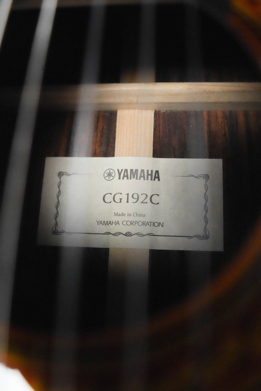 Close-up of a Yamaha CG192C Cedar/Rosewood Classical Acoustic Guitar #0188 label inside the soundhole, showing model number and cedar top, made by Yamaha, with guitar strings visible in the foreground.