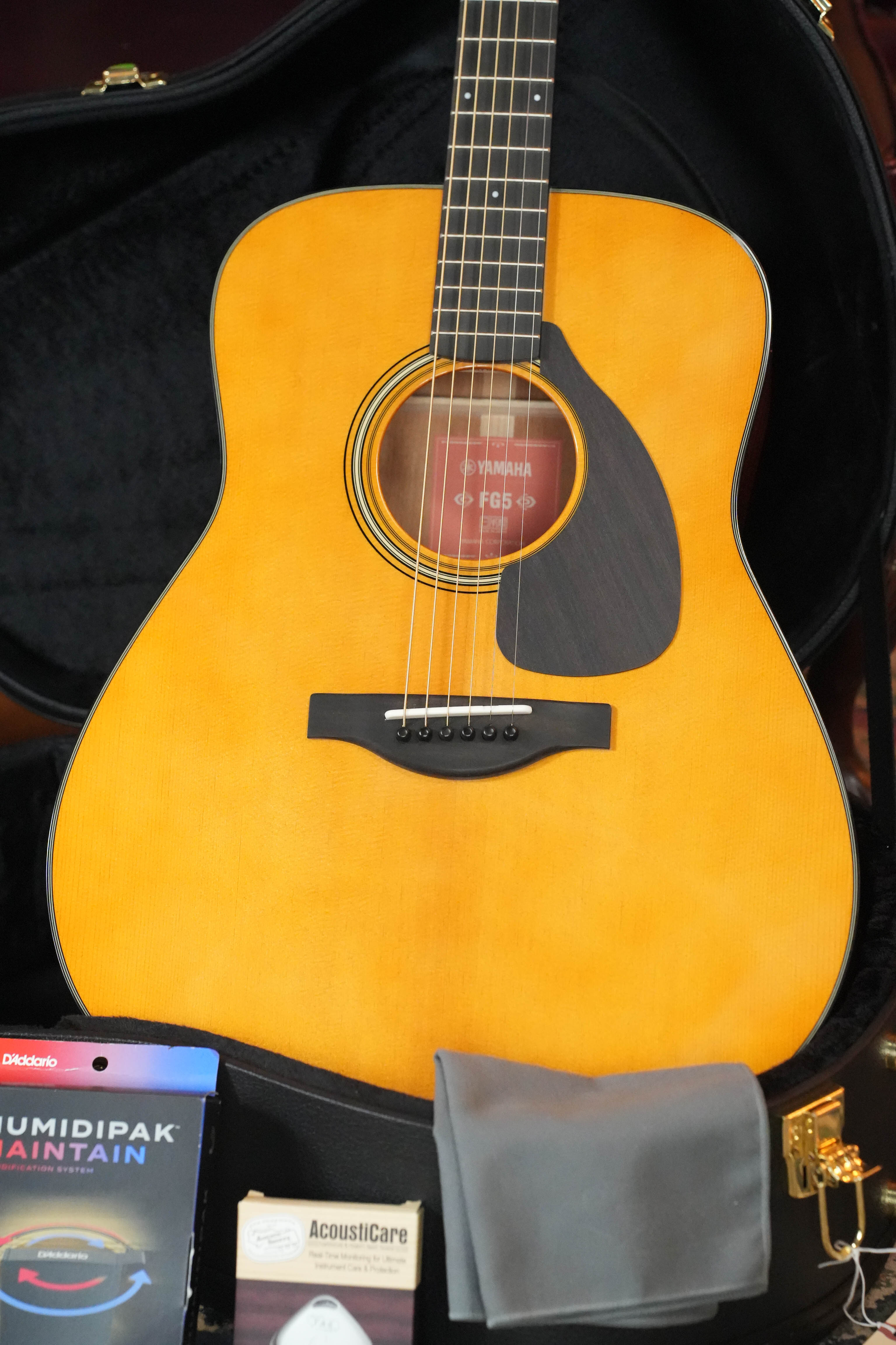 The Yamaha FG5 GL NEW Gloss Red Label Dreadnought Acoustic Guitar #732A by Yamaha features a solid Sitka spruce top, natural finish, black pickguard, and comes in a hard case with cleaning cloth, humidipak, and AcousticCare items.