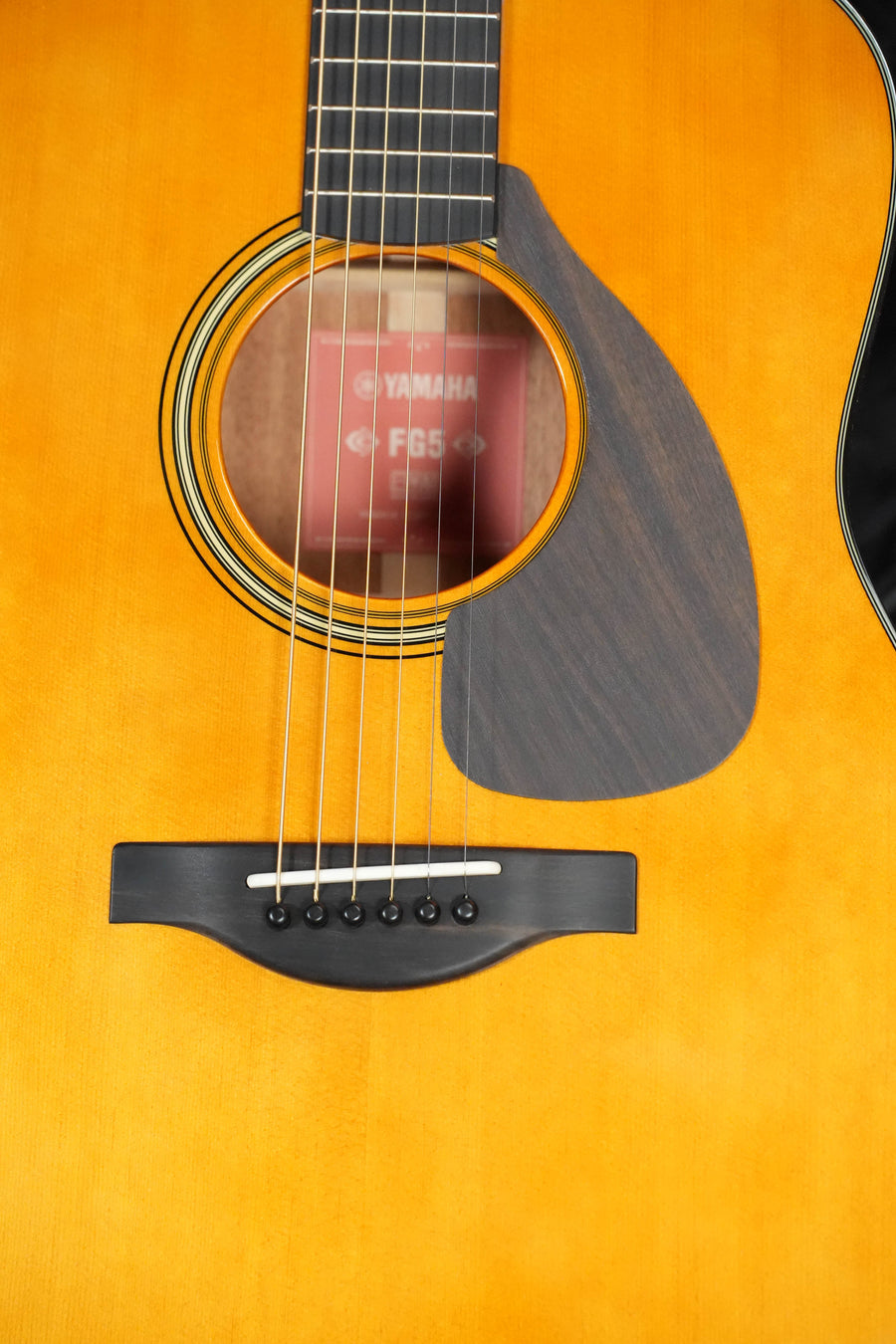 Close-up of the Yamaha FG5 GL NEW Gloss Spruce/Mahogany Red Label Dreadnought Acoustic Guitar #520A, showing its solid spruce top, soundhole with Yamaha FG5 label, strings, bridge, and partial pickguard.