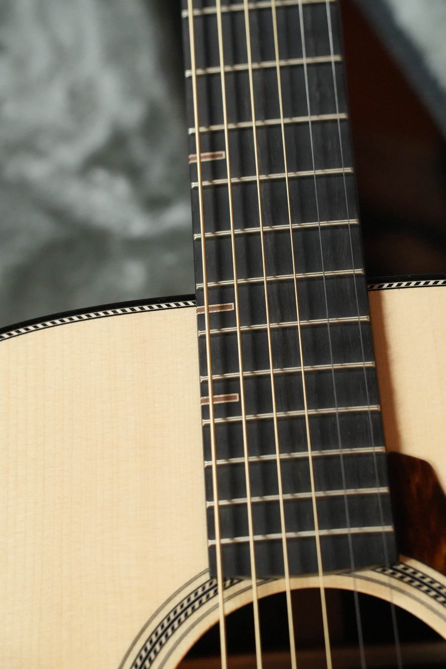 Close-up of a Yamaha FG9 R NT Natural Finish Dreadnought Acoustic Guitar #126A, highlighting its Adirondack spruce top, body, neck, detailed fretboard, and strings against a blurred background.