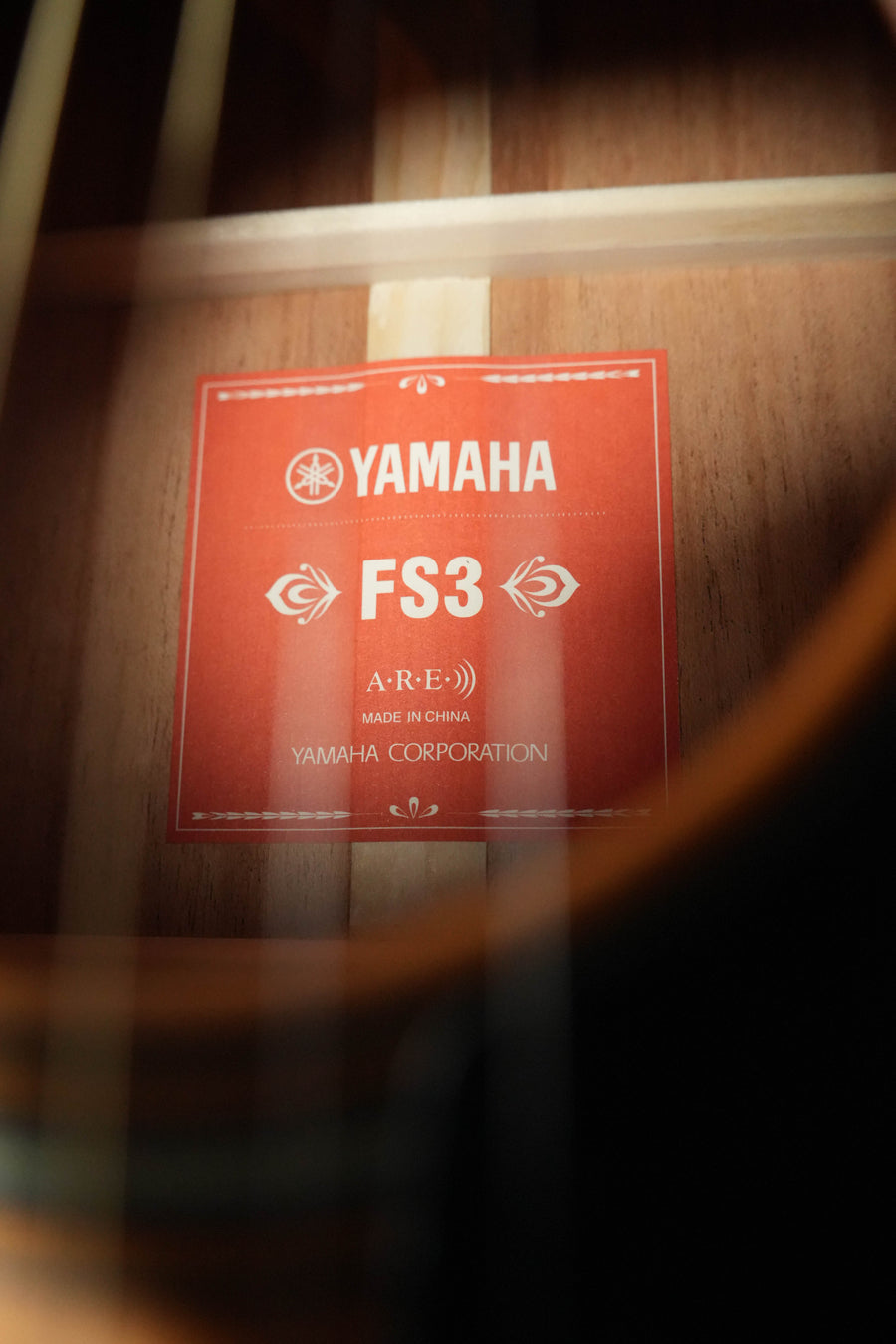 A close-up of the Yamaha FS3 Red Label Concert Acoustic Guitar #1516 soundhole shows the Yamaha brand, model FS3, A.R.E., Yamaha Corporation, and Made in China on the wood of this smaller-bodied acoustic guitar.