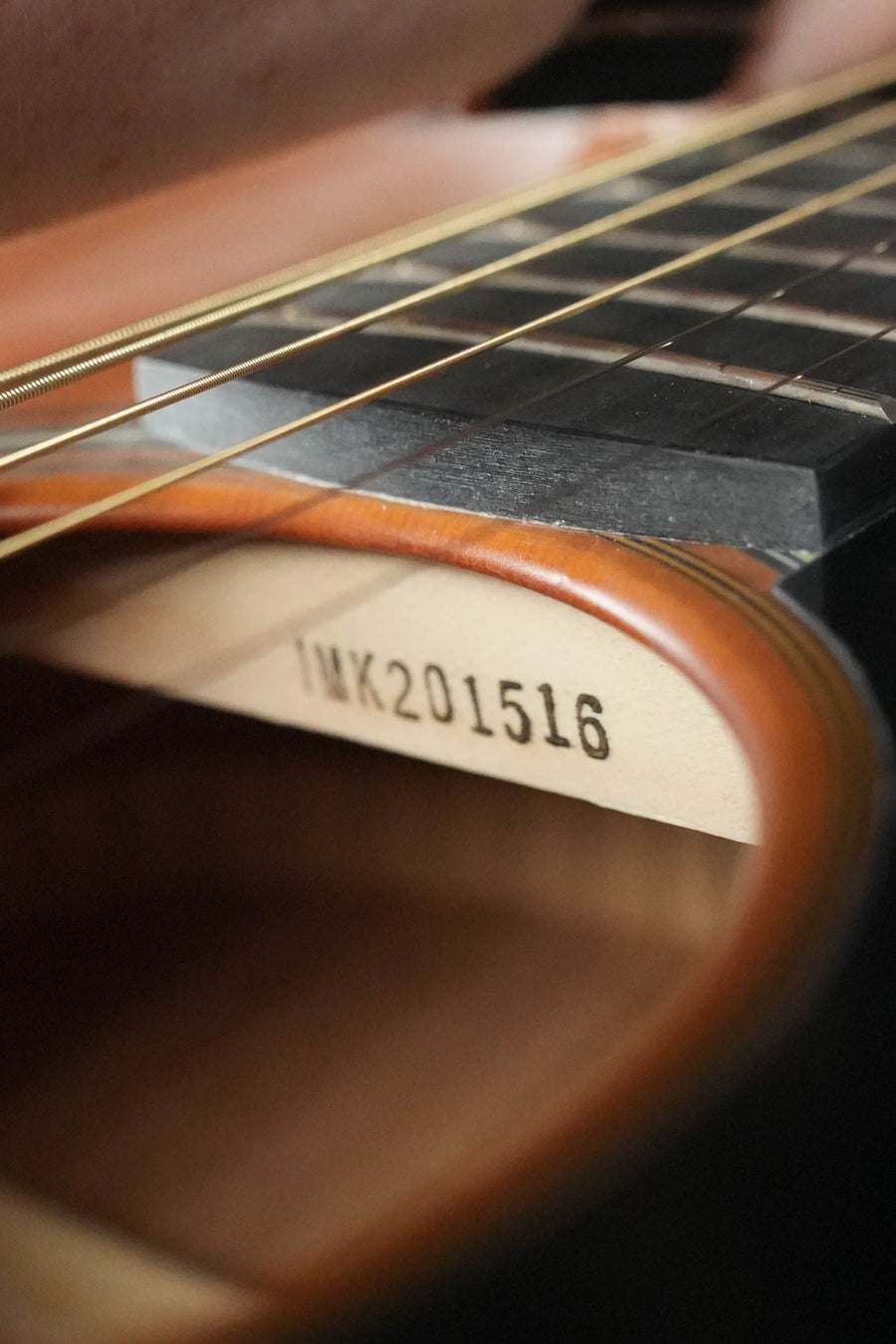 Close-up of the Yamaha FS3 Red Label Concert Acoustic Guitar #1516 by Yamaha, showing its solid Sitka spruce top, metal strings, the wooden interior, and serial number 1516 stamped inside.