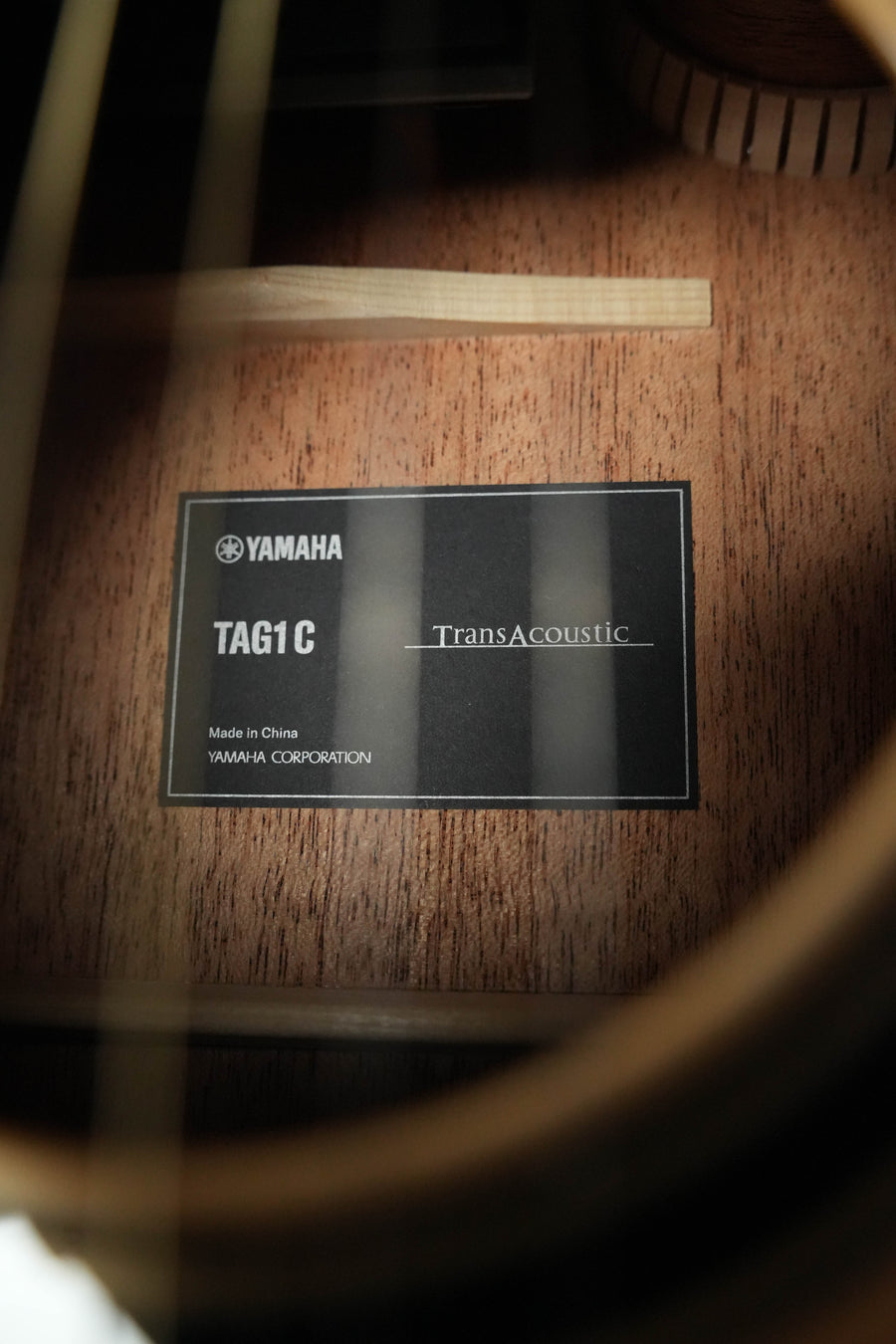 Close-up of a Yamaha TAG1 C Natural Finish Dreadnought Cutaway Acoustic-Electric Guitar label inside the body, showing model #0718, built-in effects, and noting it was made in China.