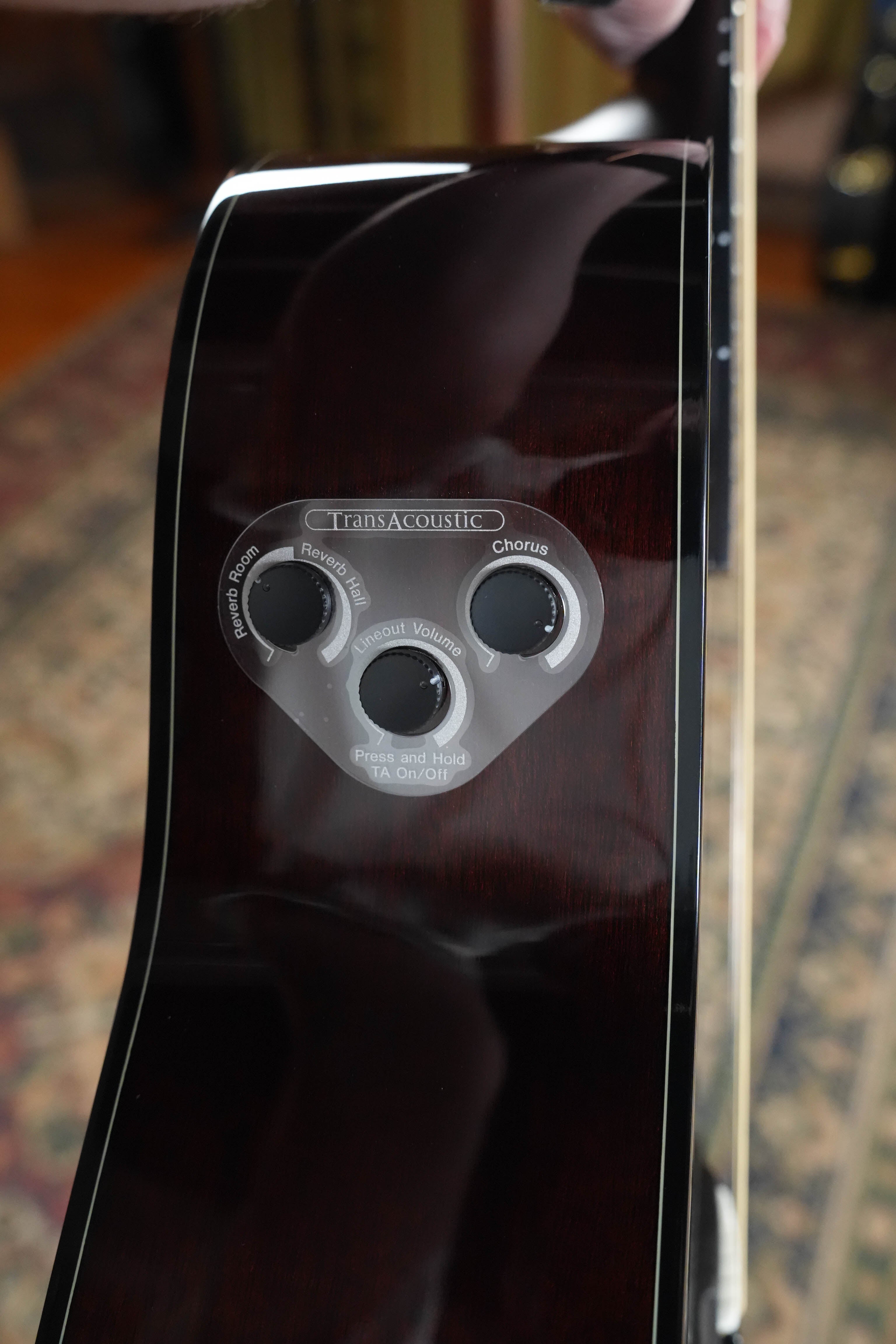 A close-up of the Yamaha TAG1E TBL TransAcoustic Dreadnought Guitar #1280 shows its built-in control panel for reverb, chorus, and volume on a dark glossy spruce and mahogany body.