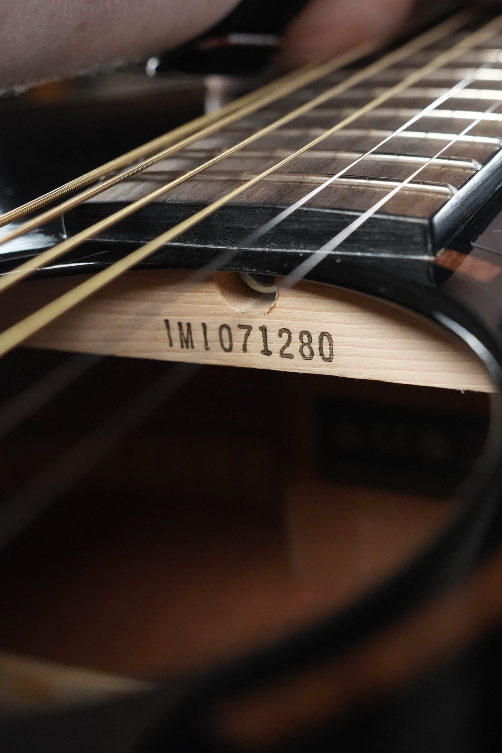 Close-up of a Yamaha TAG1E TBL Spruce/Mahogany Transacoustic Dreadnought Guitar #1280 sound hole, showing strings, fretboard, and internal label. Made with solid spruce and mahogany for rich tone. Brand: Yamaha.