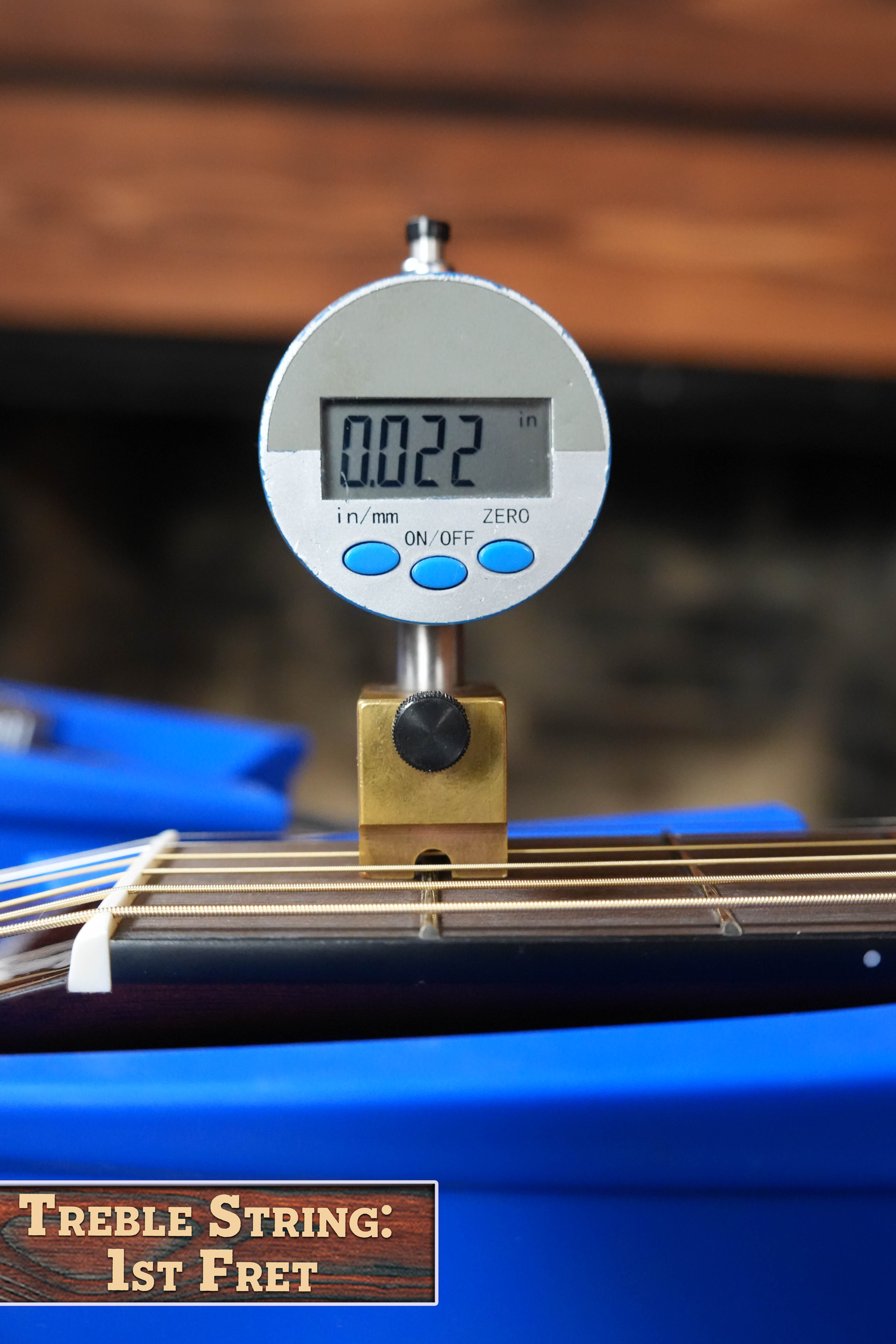 A digital gauge displays 0.022 inches while measuring the treble string action at the 1st fret of a Yamaha TAG1E TBL Spruce/Mahogany Transacoustic Dreadnought Guitar #1280. A sign reads, “Treble String: 1st Fret.”.
