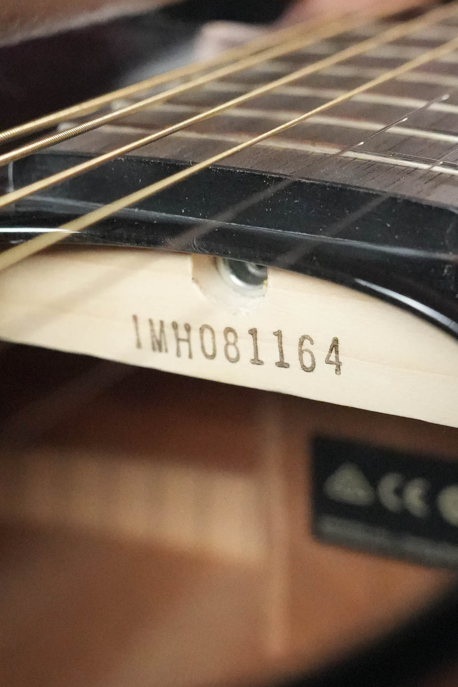 Close-up of a Yamaha TAG1E TBL TransAcoustic Dreadnought Acoustic-Electric Guitar (#1164) in Translucent Black, showing the serial number stamped inside and highlighting its innovative Yamaha TransAcoustic system.