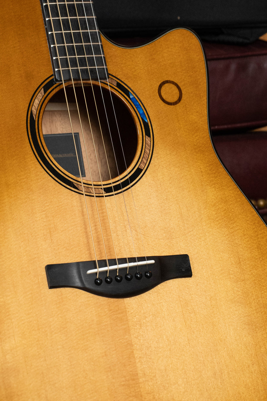 A close-up of the Yamaha TAG3C-SDB Sitka/Mahogany Sandburst Dreadnought Guitar reveals its strings, sound hole, and fingerboard, highlighting the newest TransAcoustic System by Yamaha.