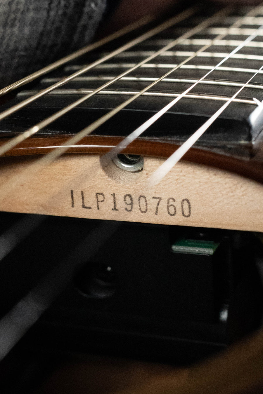 Close-up of a Yamaha TAG3C-SDB Sandburst Dreadnought guitar neck joint, showing serial number #0760 stamped on the wood beneath the strings and fretboard, featuring the NEWEST TransAcoustic System.