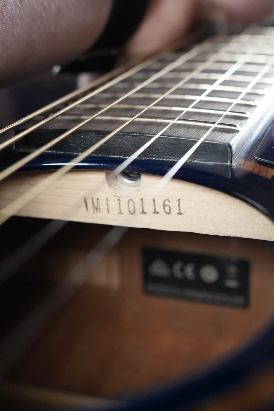 Close-up of a Yamaha TAS1E Ultra Marine Spruce/Mahogany Transacoustic Concert Guitar #1161, highlighting the strings, serial number 1161 inside, certification markings, and the TransAcoustic system within the body.