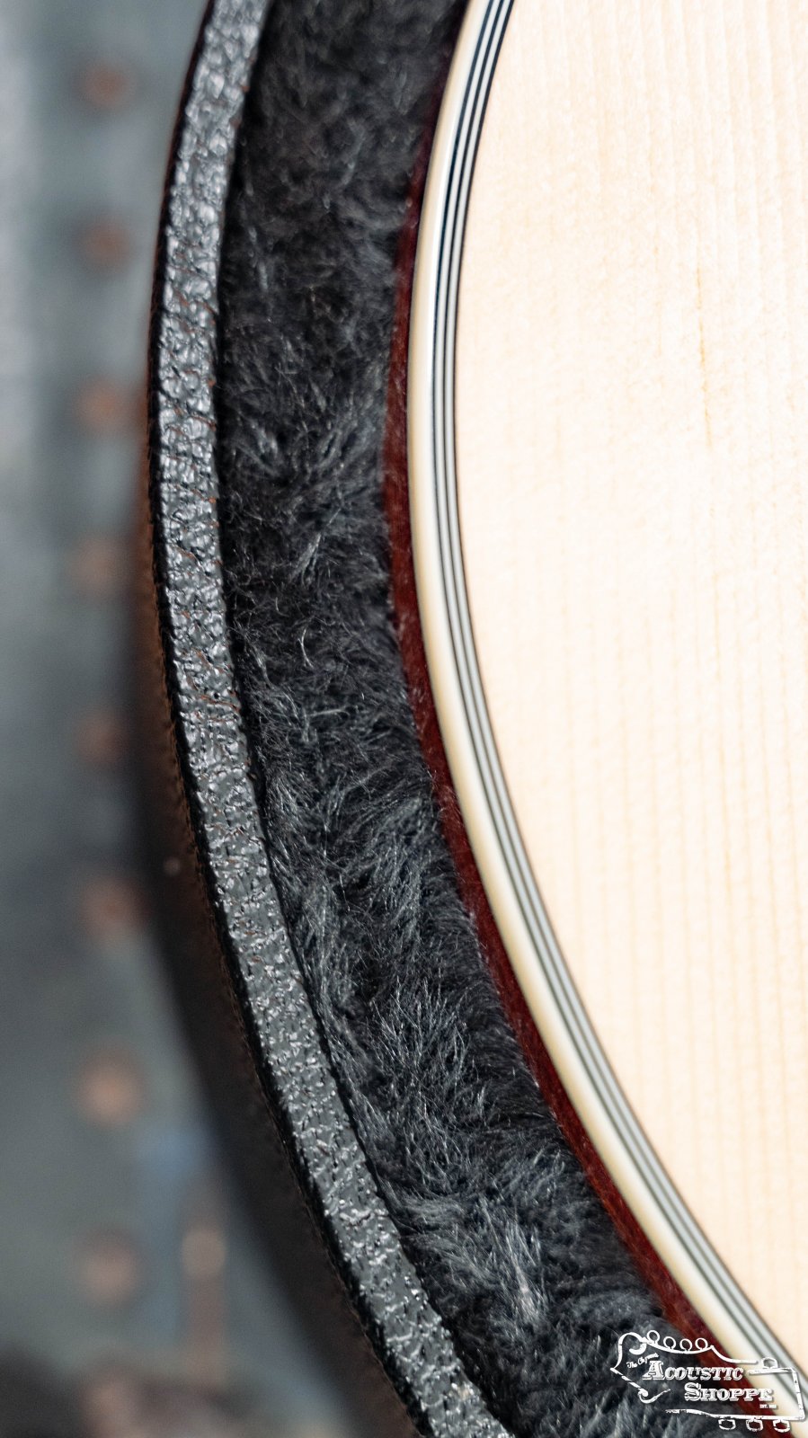 Close-up of a guitars light wood and decorative binding beside the soft lining of a TKL 7820 Premier Jumbo 6/12 String Hardshell Guitar Case by TKL.