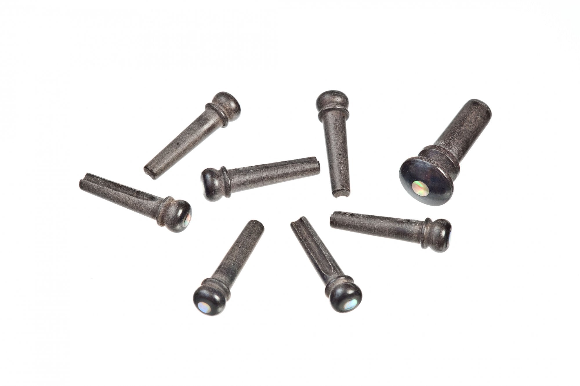 Eight D'Addario Ebony Bridge Pins w/End Pin Set - Abalone Inlay by D'Addario are scattered on a white background, with one pin set apart from the others.